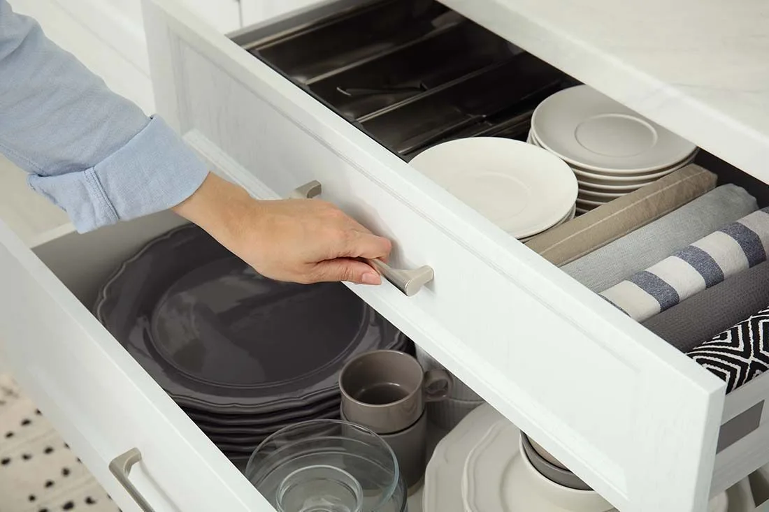 An open drawer of plates and cups in a newly refaced kitchen